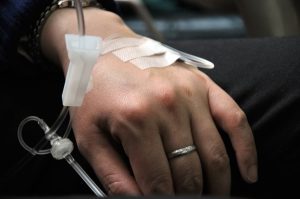 Hand of patient receiving saline solution via IV with tape holding it in place