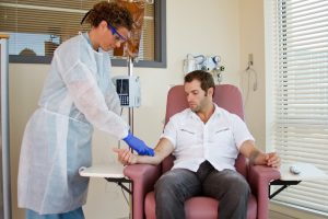 Nurse preparing patient for infusion therapy by inserting IV