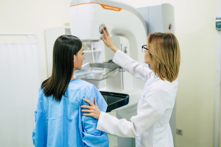Healthcare worker helps patient prepare for mammogram