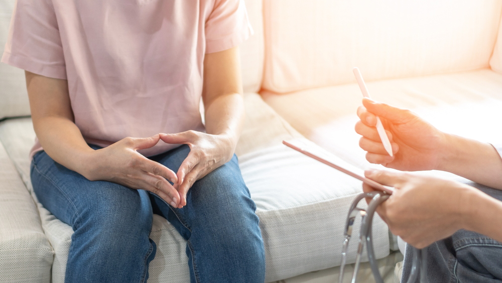 Patient sits on sofa discussing medical information with doctor
