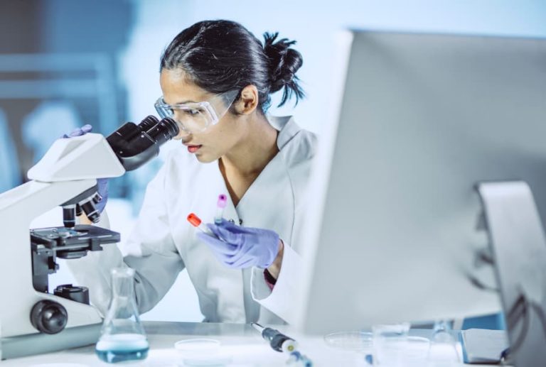 Oncologist examining cells under a microscope