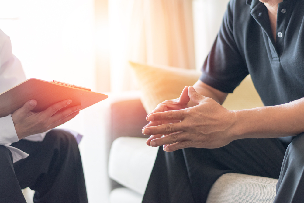 Doctor with clipboard and patient discussing testicular cancer