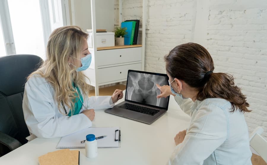 Doctor going over pelvis x-ray on computer with female patient