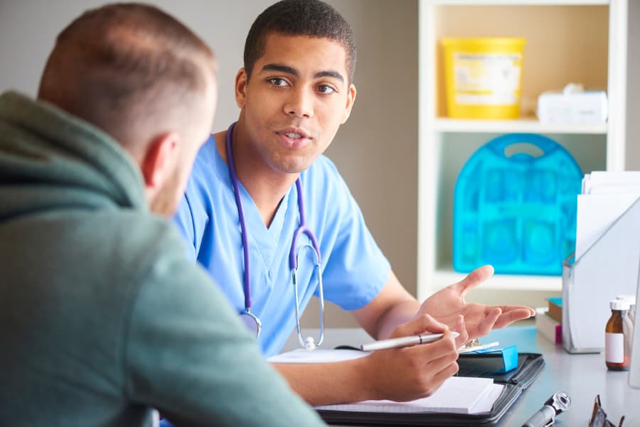 Doctor having discussion with a male patient in his 20s or 30s in medical office