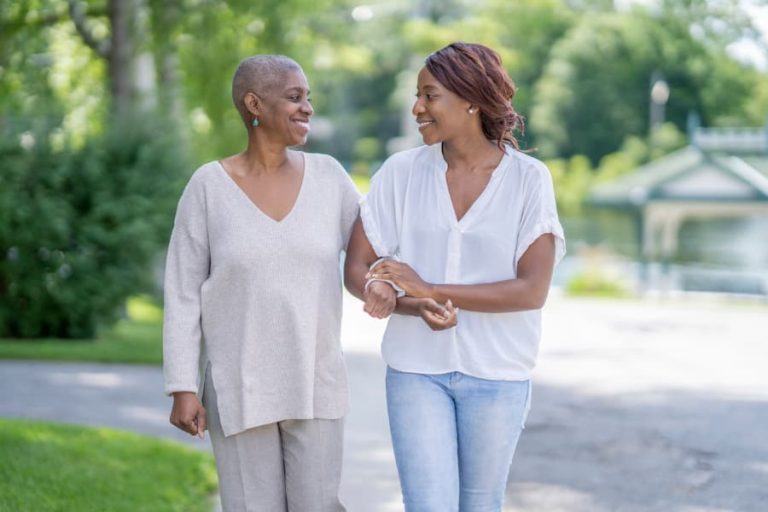 Caregiver accompanies patient with cancer during a neighborhood walk outside