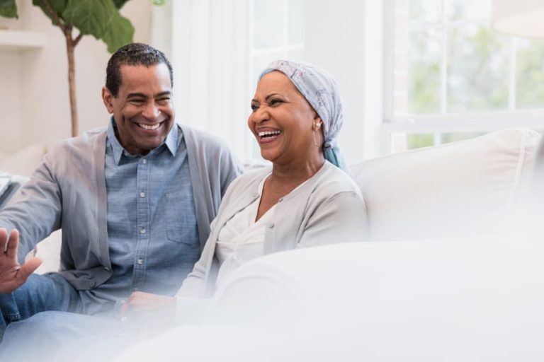 Patient and caregiver seated on a couch and smiling together
