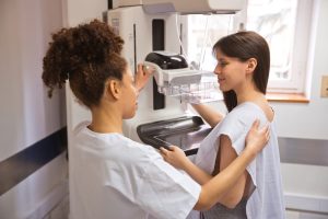 Nurse speaking with patient in gown before starting mammogram