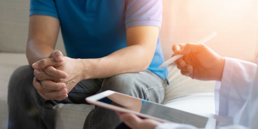 Patient sitting down with hands grasped while doctor discusses options