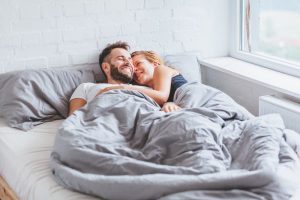 Smiling couple in bed after intimacy