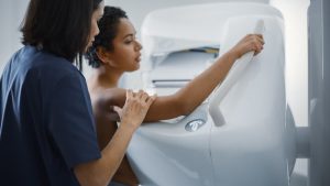 Technologist helping patient with mammogram procedure