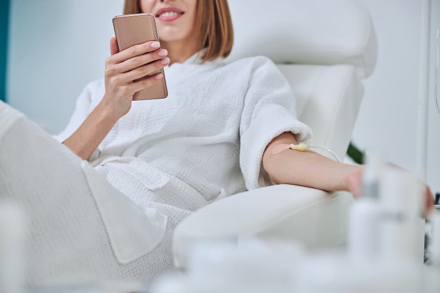 Patient using smartphone while receiving infusion therapy