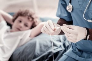 Close-up image of doctor adjusting infusion drip for child patient