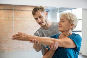 Senior woman exercising with assistance from physical therapist