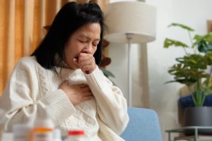 Asian-American woman coughing at home