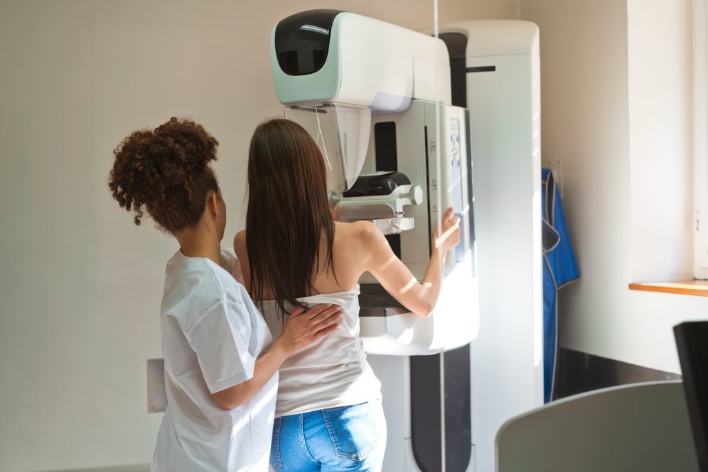 Technician assists young woman having first mammogram