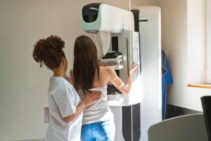 Technician assists young woman having first mammogram