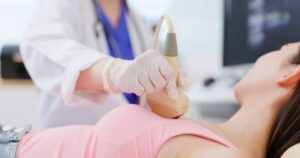 Person receiving breast ultrasound from technician in doctor’s office