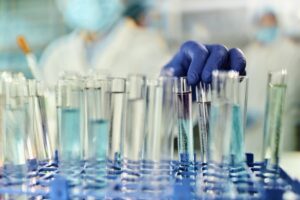 Close-up of gloved hand taking test tube in laboratory