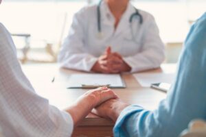 Couple holding hands at doctor’s office during fertility counseling appointment