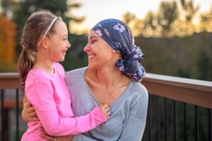 Happy child hugging mother who is in cancer remission